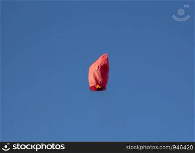 Flying red Chinese heart-shaped flashlight flies, Flying lantern, hot-air balloon. Lantern flies up high in the blue sky.