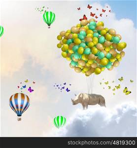 Flying rhino. Rhino flying high in sky on bunch of colorful balloons