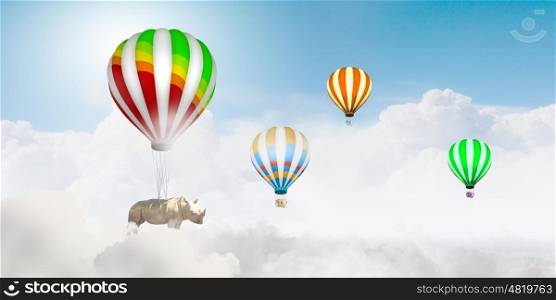 Flying rhino. Rhino flying high in sky on colorful aerostat