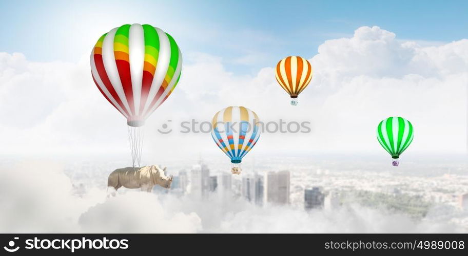 Flying rhino. Rhino flying high in sky on colorful aerostat