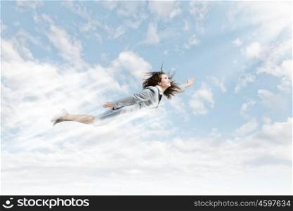Flying superwoman. Young pretty businesswoman flying in blue sky