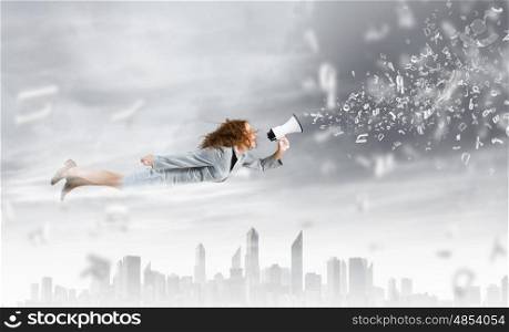 Flying superwoman. Young pretty businesswoman flying in blue sky sreaming in megaphone