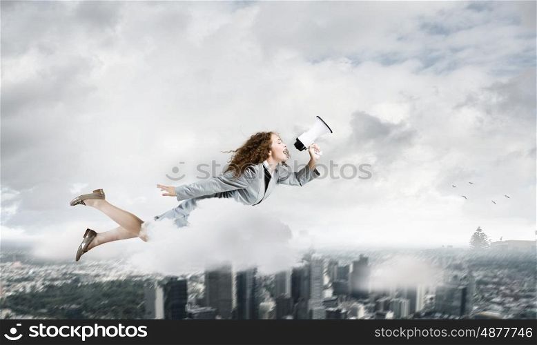 Flying superwoman. Young pretty businesswoman flying in blue sky sreaming in megaphone