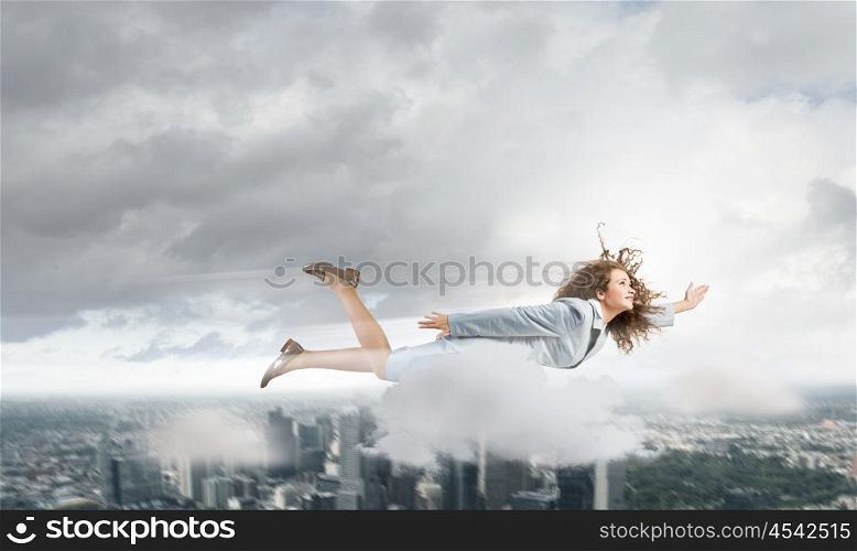 Flying superwoman. Young pretty businesswoman flying in sky above city