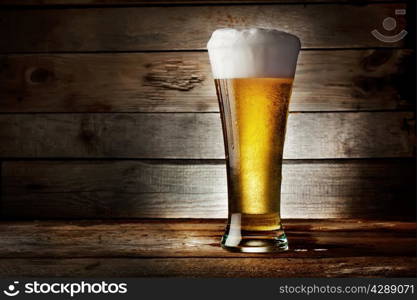 Foam glass of lager beer on a wooden background