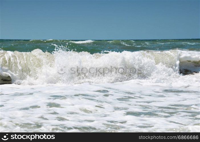 Foam on a sea wave, a view from the shore to a splash of water