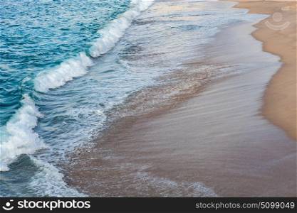 Foamed blue waves breaking in the beach