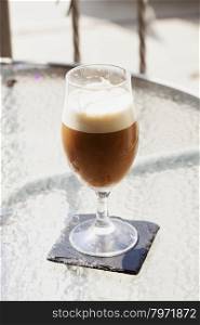 Foamy cocktail in glass over outdoor table, vertical image