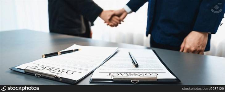 Focus closeup panorama business contract paper with pen, while two professionals shake hand in blurred background, signifying successful negotiation and partnership agreement with handshaking. Prodigy. Focus closeup business contract paper with pen with blur handshaking. Prodigy