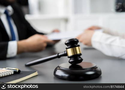 Focus closeup wooden gavel on blur background of lawyer colleagues or drafting legal documents on their workplace at law firm office. Hammer of justice for righteous and equality judgment. Equilibrium. Focus closeup wooden gavel on blur background of legal team. Equilibrium