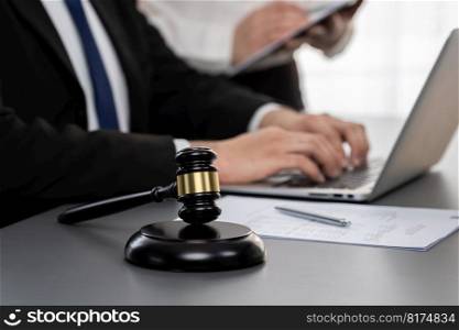 Focus gavel hammer for righteous and equality judgment with blur background of lawyer colleagues or legal team working with laptop, drafting legal documents for litigation at law firm. Equilibrium. Focus gavel with blur lawyer colleagues working at law firm. Equilibrium