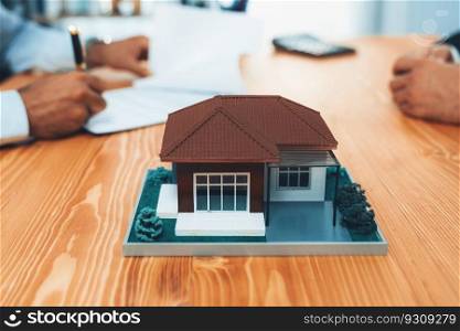 Focus house sample house model with blurred satisfied buyer sign house loan or purchase agreement with smile, finalizing the deal in the background with real estate agent or landlord. Fervent. Focus house sample house model with blurred satisfied signing contract. Fervent