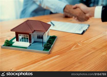 Focus house sample or model with blur background of buyer handshaking with real estate agent. House loan contract with banker and client hand shake as symbol of successful agreement deal. Fervent. Focus house sample or model with blur background of handshaking. Fervent