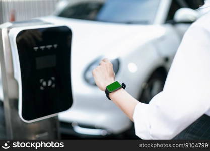 Focus mockup smartwatch with green screen for hologram or interface copyspace of electric car battery that recharging at charging station. Progressive mockup device mockup with green screen.. Progressive mockup green screen watch display EV car battery status.