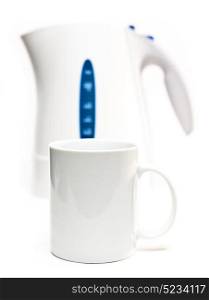 Focus on a tea mug. Electric tea kettle on a white background and a mug