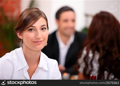 Focus on a woman sitting in a restaurant with other diners in the background
