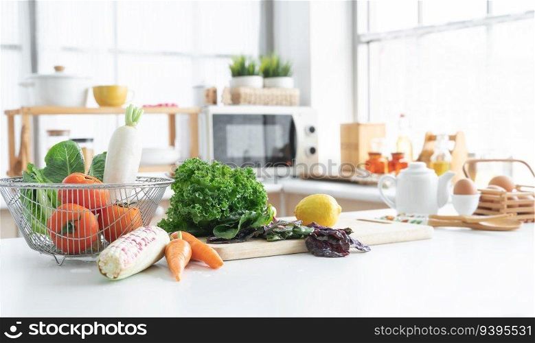 Focus on fresh green vegetable in home kitchen, yellow lemon placed on cutting board, carrots, corn, tomatoes, white radish, cos salad in basket, Eggs, seasoning in blur background. Healthy food