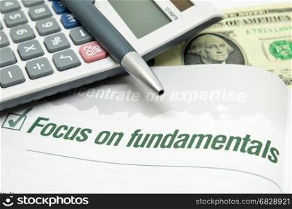 Focus on fundamentals printed on book with calculator and pen.