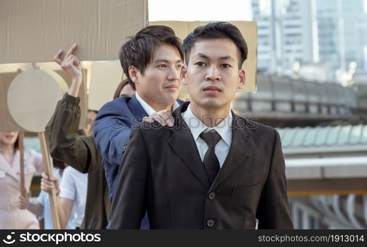 Focus on male leader wearing formal suit and walking with blur background of protesters