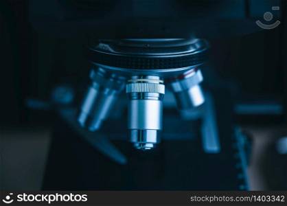 Focus on microscope with metal lens for experiments, educational demonstrations in clinical laboratories. Medicine researching concept. Blurred background