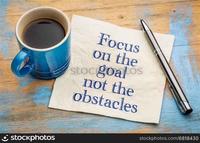 Focus on the goal, not obstacles - handwriting on a napkin with a cup of espresso coffee