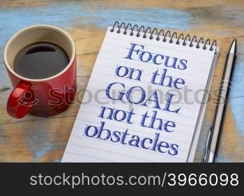 Focus on the goal, not the obstacles - inspirational advice on a spiral notebook with a cup of coffee