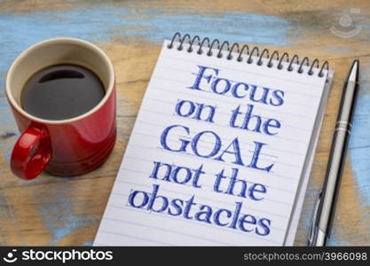 Focus on the goal, not the obstacles - inspirational advice on a spiral notebook with a cup of coffee