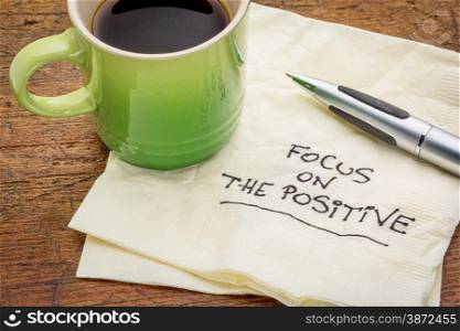 focus on the positive - motivational words handwritten on a napkin with a cup of espresso coffee