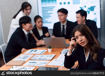 Focus portrait of female manger, businesswoman in the harmony meeting room with blurred of colleagues working together, analyzing financial paper report and dashboard data on screen in background.. Focus portrait of asian female manger with blurred background in harmony.