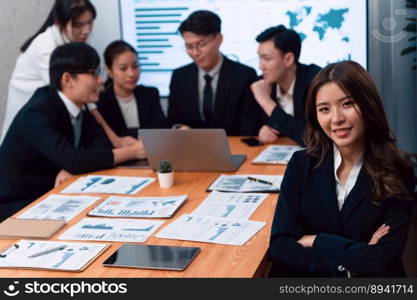 Focus portrait of female manger, businesswoman in the harmony meeting room with blurred of colleagues working together, analyzing financial paper report and dashboard data on screen in background.. Focus portrait of asian female manger with blurred background in harmony.