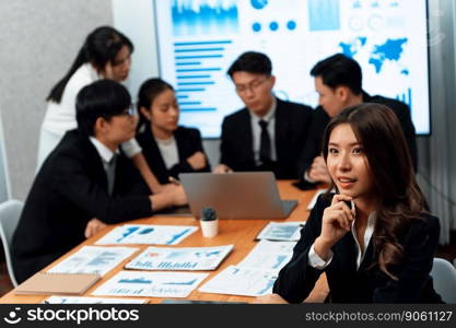 Focus portrait of female manger, businesswoman in the harmony meeting room with blurred of colleagues working together, analyzing financial paper report and dashboard data on screen in background.. Focus portrait of asian female manger with blurred background in harmony.