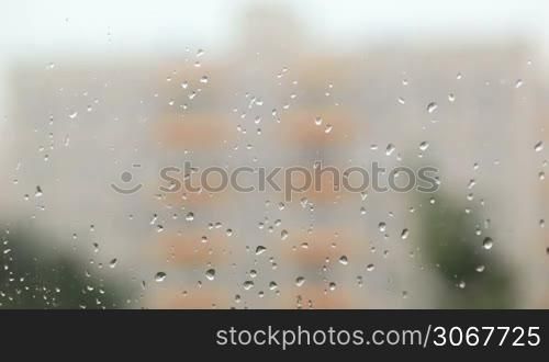 Focus pulling from glass with rain drops to the building.