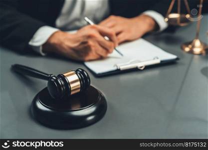 Focus symbols of justice, gavel hammer and scale balance on blurred background of lawyer or judge signing legal document at his desk for integrity and fairness of the legal system. equility. Focus symbols of justice on blurred background of lawyer signing. equility