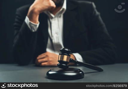 Focus wooden gavel hammer with burred background of lawyer in black suit sit on his office desk, symbol of legal justice and integrity, balanced and ethical decision in court of law equility. Focus wooden gavel with burred background of lawyer. equility