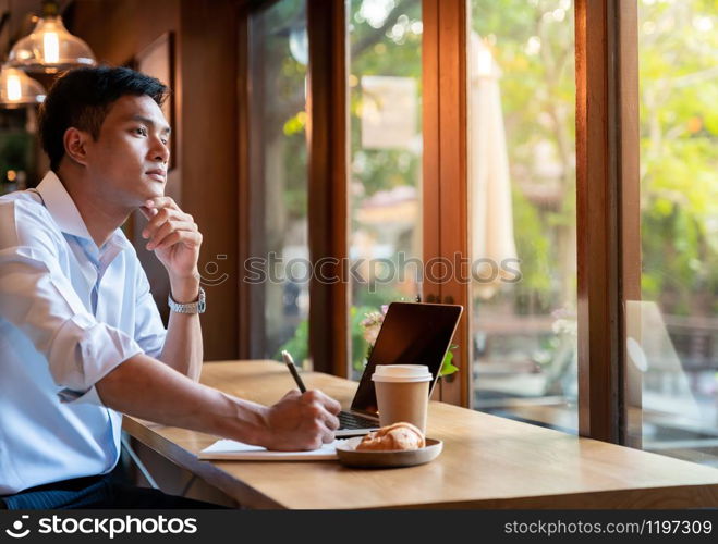 Focused asian college student working with laptop in cafe preparing for test or exam.