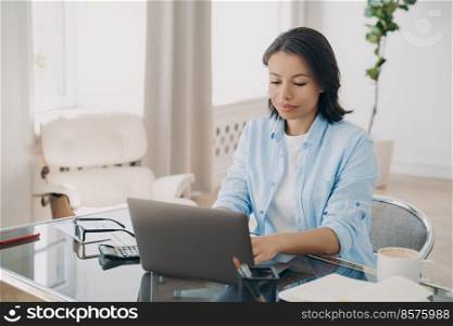 Focused businesswoman entrepreneur using computer, working online on project, sitting at office desk. Professional woman typing email on laptop on workplace. E-business, distant job concept.. Businesswoman entrepreneur working online, typing email on laptop sitting at office desk. E-business