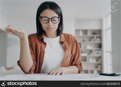 Focused female in glasses working with financial documents at home. Businesswoman calculating expenses, planning household budget for economy saving money, sitting at desk.. Female wearing glasses calculating expenses, planning household budget for saving money at home