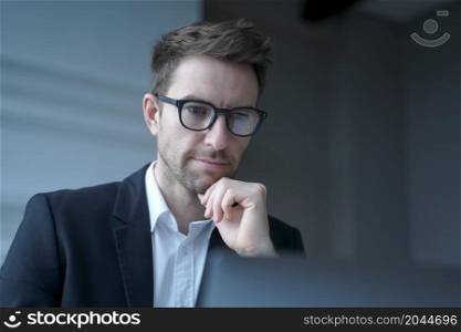 Focused German man family lawyer in formal wear thoughtfully looking at computer monitor while distantly working from modern home office carefully reading clients&rsquo; prenuptial agreement for signature. Focused German man family lawyer in formal wear thoughtfully looking at computer monitor