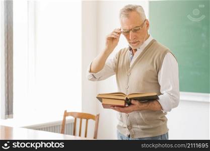 focused male professor glasses reading book classroom