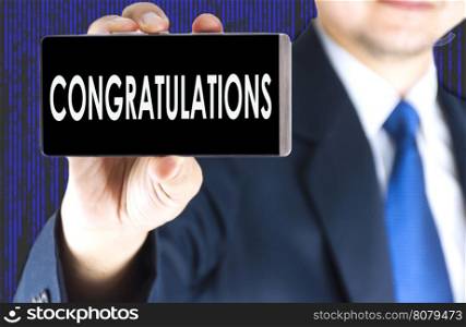 Focused of congratulations word on mobile phone screen in blurred young businessman hand and digital technology background