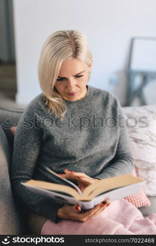 Focused woman reading book on the couch. Resting, relax and entertainment. Studying and education.. Woman reading book on the couch.