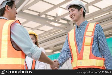 Focusing on male engineer smiling and shake his hand to celebrate his successful project at construction site.