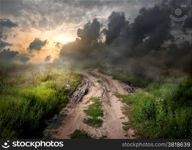 Fog and dirt over country road at sunset