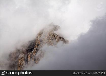 Fog clouds obscure view of mountain wall in mountains
