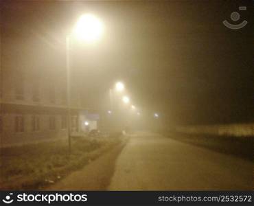 Fog laying over town. Street lamps in mist