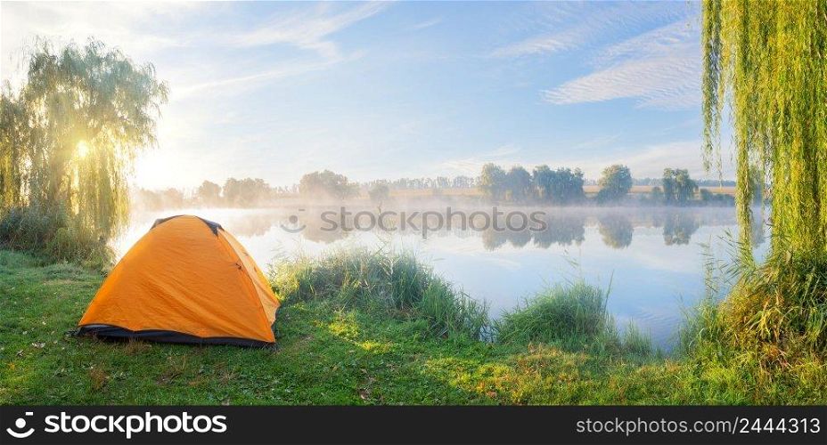 Foggy lake shore with the orange tent in morning sun. Foggy lake shore with orange tent in morning sun