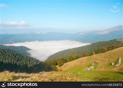 Foggy mountain landscape at sunrise in Carpathians. Old wooden house in a mountain valley.