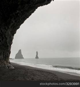 Foggy seascape, framed rock stacks from sea cave