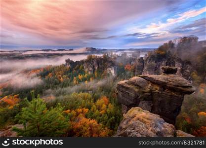 Foggy sunrise in the Saxon Switzerland, Germany, view from the Bastei lookout point.. Foggy sunrise in the Saxon Switzerland, Germany, view from the Bastei lookout point. The Bastei is a tourist attraction for over 200 years.