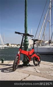                        Foldable E-bike against pole in harbour        